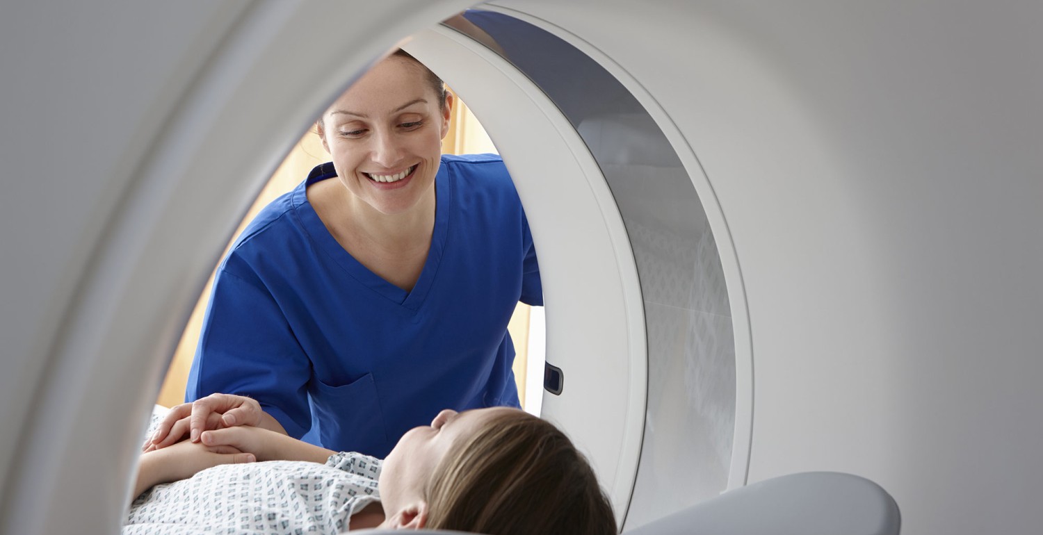 Radiographer smiling at girl inside CT scanner